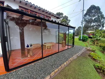 a glass house with a dog sitting on a patio at Finca Alejandria in Guatapé