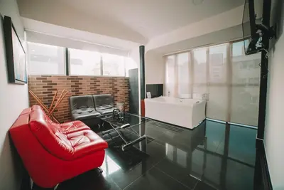 a living room with a red chair and a sink at Provenza Lofts in Medellín