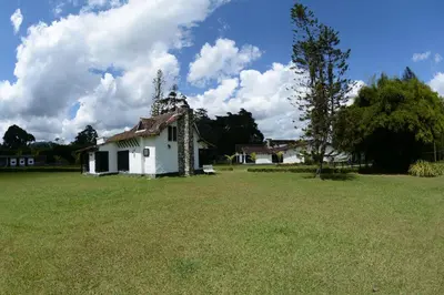 an old white house in a grassy field at Casa Finca Corales Llano Grande 2 in Rionegro