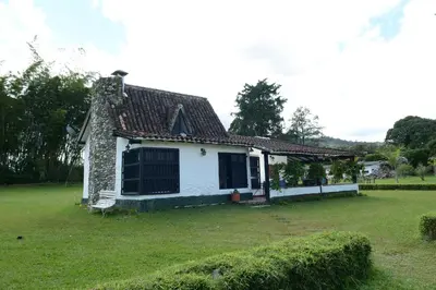 a small white house with a green yard at Casa Finca Corales Llano Grande 2 in Rionegro
