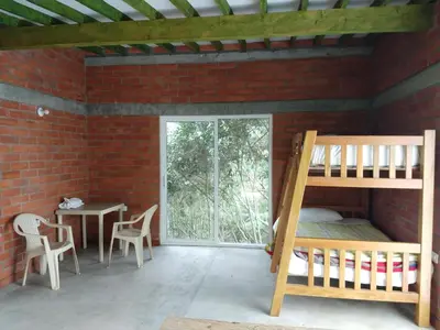 a room with a bunk bed and a table and chairs at Hospedaje Rural Misia Emilia in Medellín