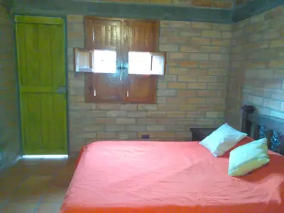 a bedroom with a red bed and a brick wall at Hospedaje Rural Misia Emilia in Medellín