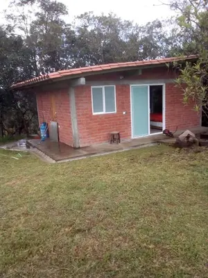 a small red brick house with a yard at Hospedaje Rural Misia Emilia in Medellín