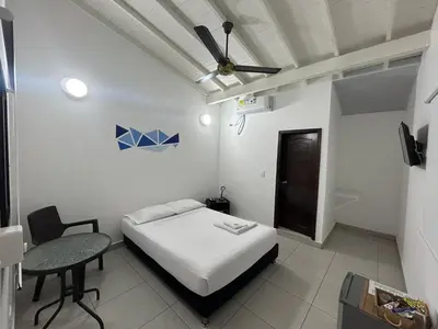 a bedroom with a bed and a table and a ceiling fan at Hotel Puerto Azul in Puerto Berrío