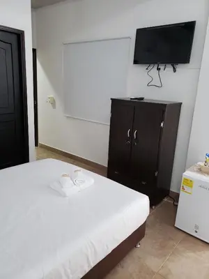 a bedroom with a bed and a flat screen tv at Hotel Puerto Azul in Puerto Berrío