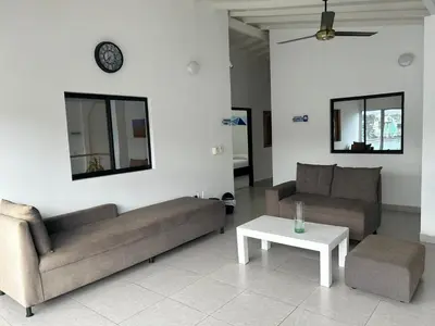 a living room with two couches and a table and a clock at Hotel Puerto Azul in Puerto Berrío