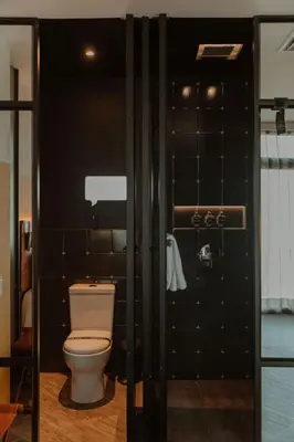a bathroom with a toilet and a black tiled wall at The Click Clack Hotel Medellín in Medellín