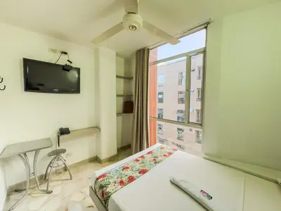 a room with a bed and a tv and a window at Hotel Macedonia Plaza Medellin in Medellín
