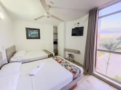 two beds in a room with a large window at Hotel Macedonia Plaza Medellin in Medellín