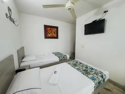 a room with two beds and a flat screen tv at Hotel Macedonia Plaza Medellin in Medellín