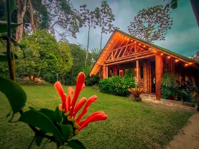 a house with a red flower in front of it at Cabaña Manantial del Turpial in Jardin
