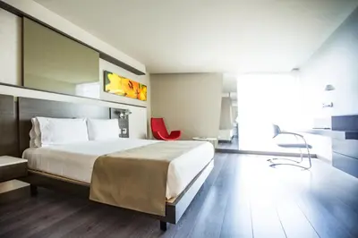 a hotel room with a bed and a red chair at Inntu Hotel in Medellín