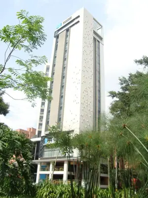 a tall white building with trees in front of it at Inntu Hotel in Medellín