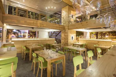 a restaurant with wooden tables and green chairs at Inntu Hotel in Medellín