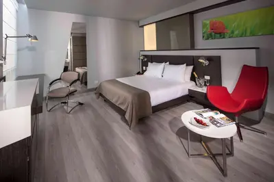 a hotel room with a bed and a red chair at Inntu Hotel in Medellín
