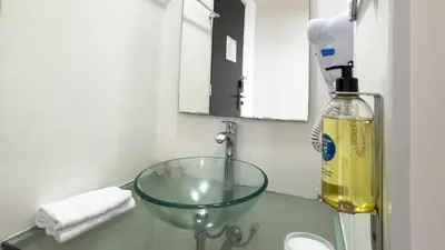 a bathroom with a glass sink and a bottle of oil at Hotel Benidorm in Manizales