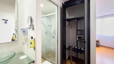 a bathroom with a glass shower with a mirror at Hotel Benidorm in Manizales