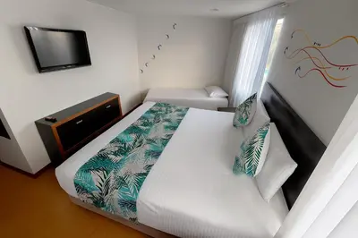 a bedroom with a white bed and a tv at Hotel Benidorm in Manizales