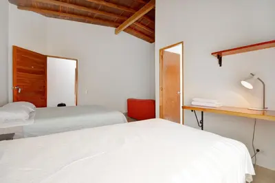 a bedroom with two beds and a desk with a mirror at Black Sheep Medellin in Medellín