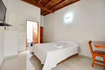 a white bedroom with a bed and a wooden chair at Black Sheep Medellin in Medellín