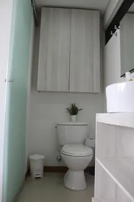 a white bathroom with a toilet and a cabinet at LLanogrande Aparta Estudio Puerto Bulevar in Rionegro