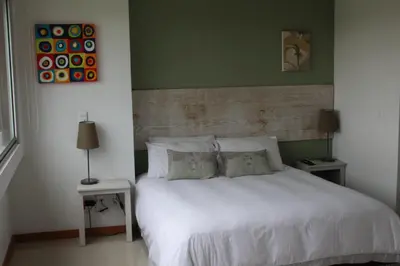 a bedroom with a white bed with two tables and two lamps at LLanogrande Aparta Estudio Puerto Bulevar in Rionegro