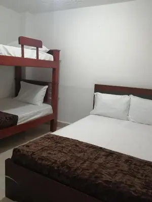 a bedroom with two bunk beds with white sheets and a bedskirts at Hotel Sol del Estadio in Medellín