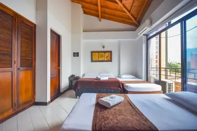 a hotel room with three beds and a balcony at Hotel Estadio Real in Medellín