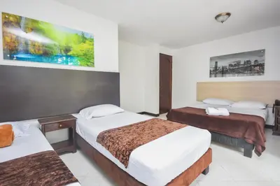 a hotel room with two beds and a painting on the wall at Hotel Estadio Real in Medellín
