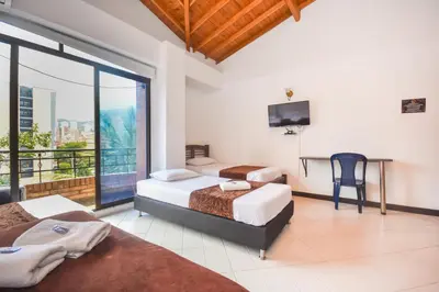 a bedroom with two beds and a desk and a tv at Hotel Estadio Real in Medellín
