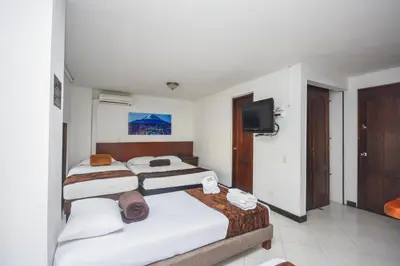 a bedroom with two beds and a flat screen tv at Hotel Estadio Real in Medellín