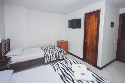 a hotel room with two beds and a television at Hotel Estadio Real in Medellín