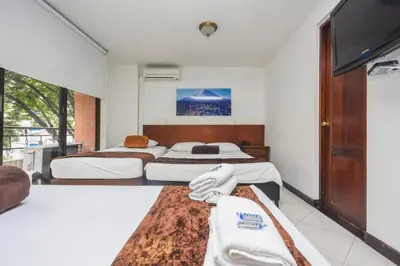 a bedroom with two beds and a tv at Hotel Estadio Real in Medellín
