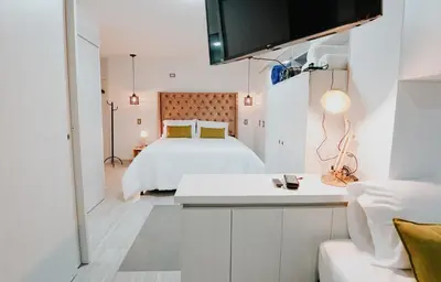 a white bedroom with a bed and a white table at Hotel Balcones del Estadio in Medellín