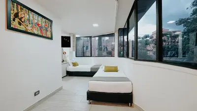 a room with two beds and large windows at Hotel Balcones del Estadio in Medellín