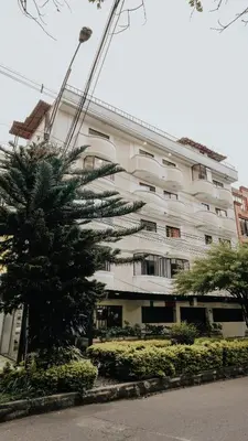a large white building with a palm tree in front of it at Hotel Balcones del Estadio in Medellín