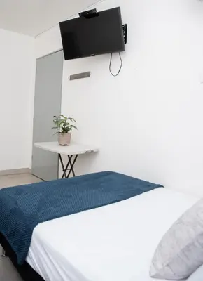 a bedroom with a bed with a tv on the wall at Hotel Alcazar in Medellín