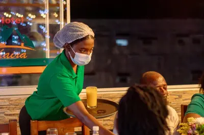 a woman wearing a mask sitting at a table at Hotel Shaira 2 in Quibdó