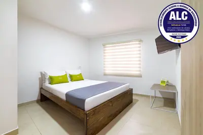 a bedroom with a bed with yellow pillows and a window at Ayenda Casa Megua in Medellín