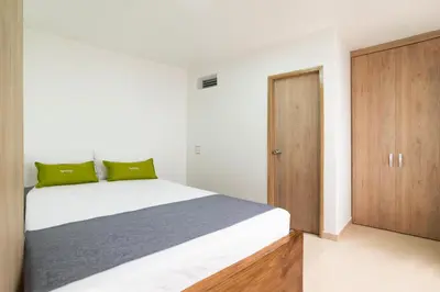 a bedroom with a white bed and a wooden cabinet at Ayenda Casa Megua in Medellín