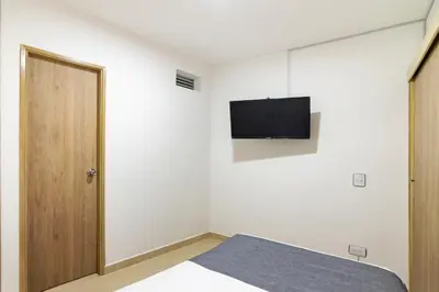 a bedroom with a bed and a tv on the wall at Ayenda Casa Megua in Medellín