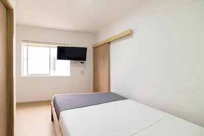 a bedroom with a bed and a tv on a wall at Ayenda Casa Megua in Medellín