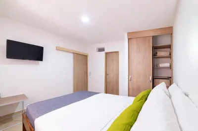 a bedroom with a bed and a tv on the wall at Ayenda Casa Megua in Medellín