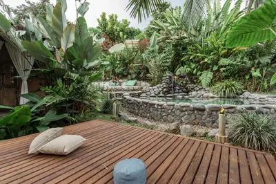 a garden with a wooden deck and a pond at Cabañas en la montaña Viga Vieja in San Peregrino