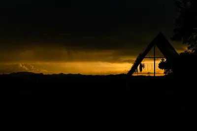 a sunset behind a tent with the sky in the background at Cabañas en la montaña Viga Vieja in San Peregrino