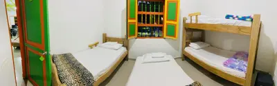 a room with three bunk beds and a book shelf at casa hostal las palmeras in Guatapé