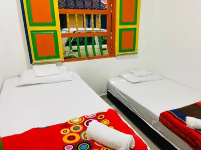 two beds in a room with two windows at casa hostal las palmeras in Guatapé
