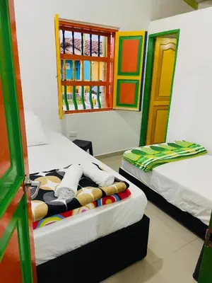 a room with two beds and a window at casa hostal las palmeras in Guatapé
