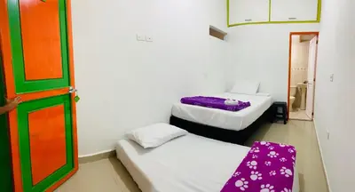 two beds in a small room with a door at casa hostal las palmeras in Guatapé