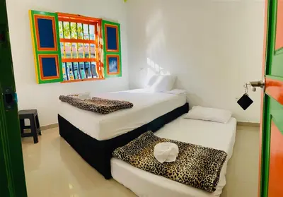 a room with two beds and a cheetah print sheets at casa hostal las palmeras in Guatapé